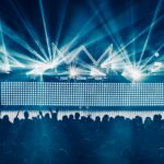 An electrifying concert atmosphere featuring dynamic laser lights and a vibrant crowd enjoying live music.