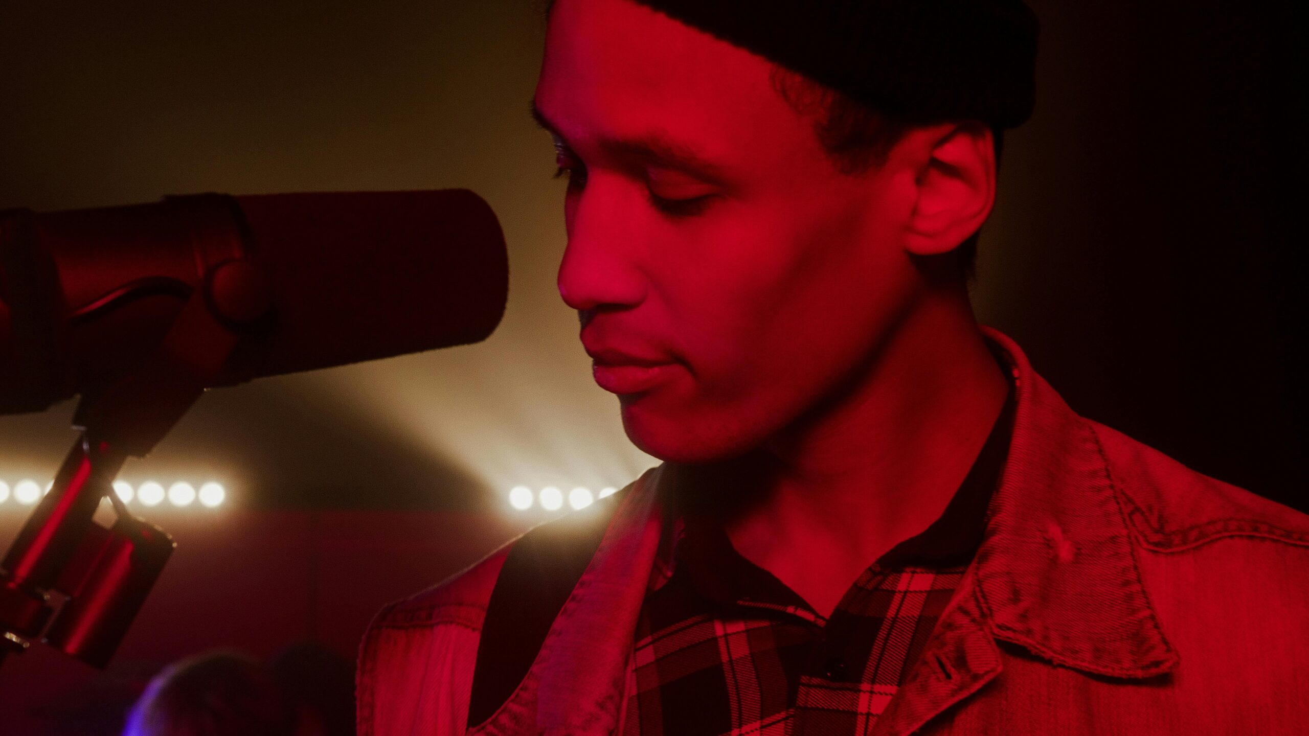 Oferta Close-up of a male singer performing under dramatic red stage lighting.